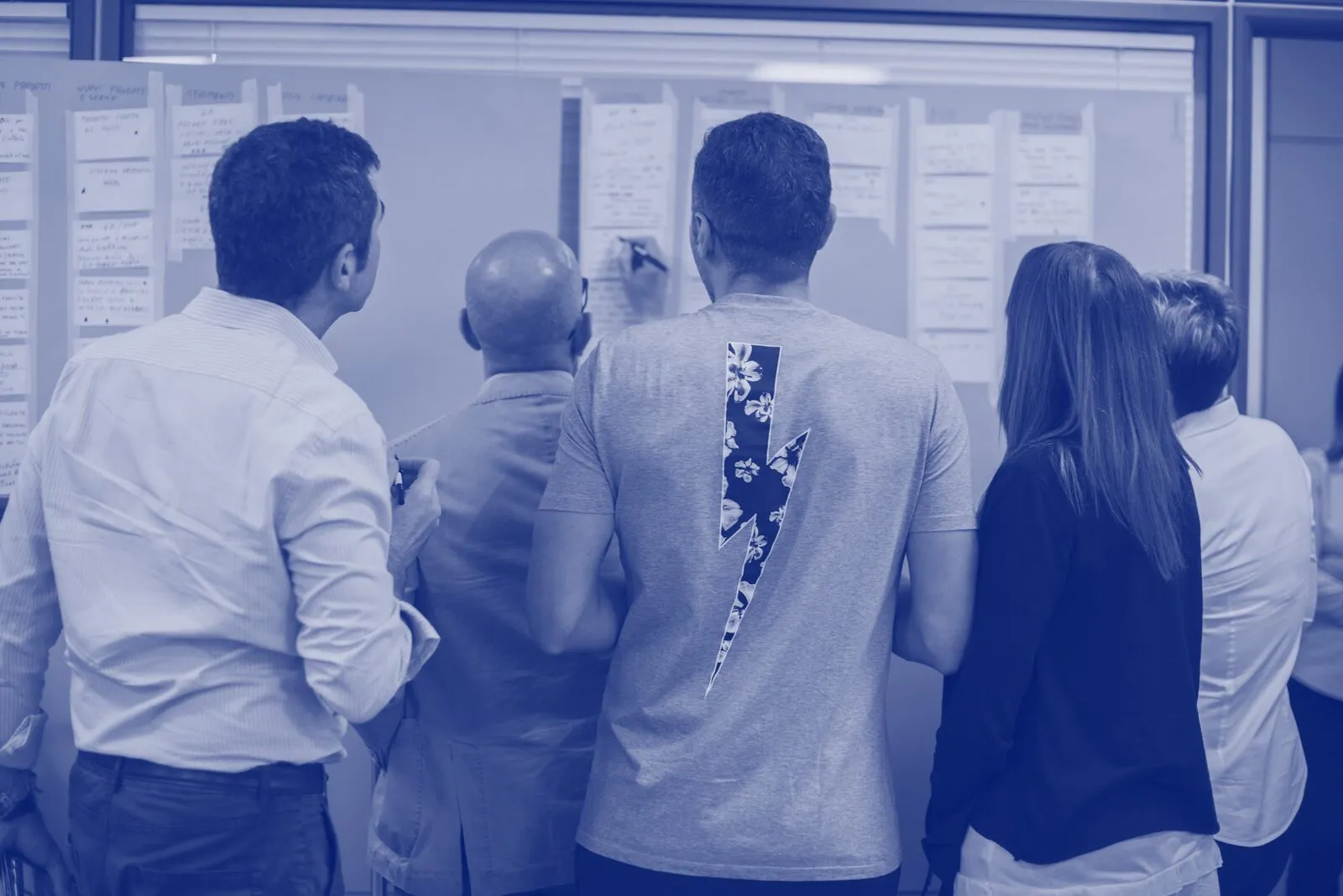 A team working at a planning wall of notes, seen from behind