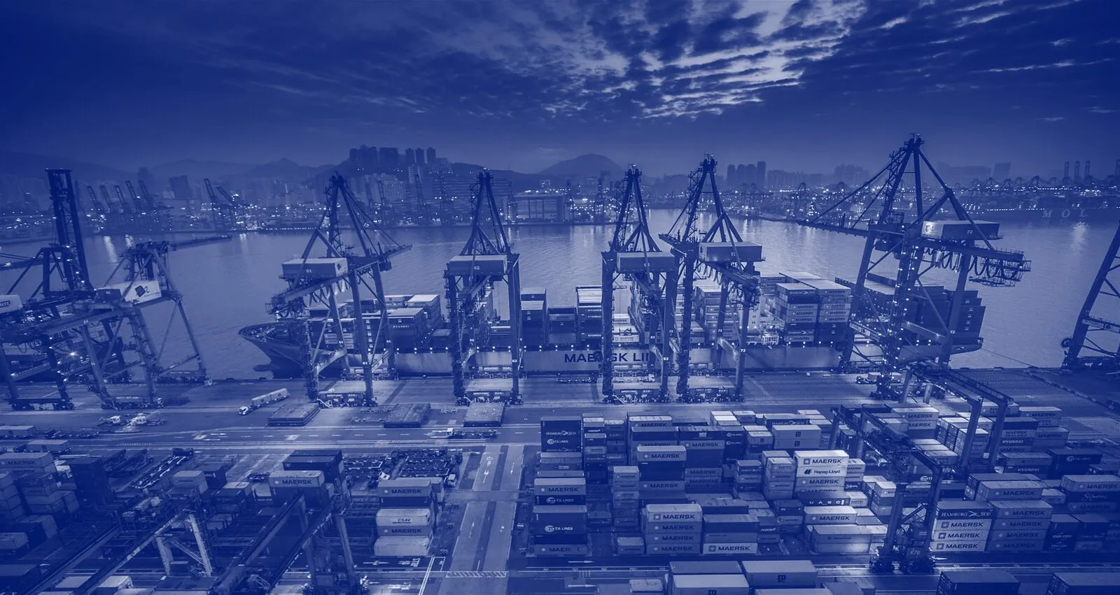 Container port with cranes and stacked containers at dusk